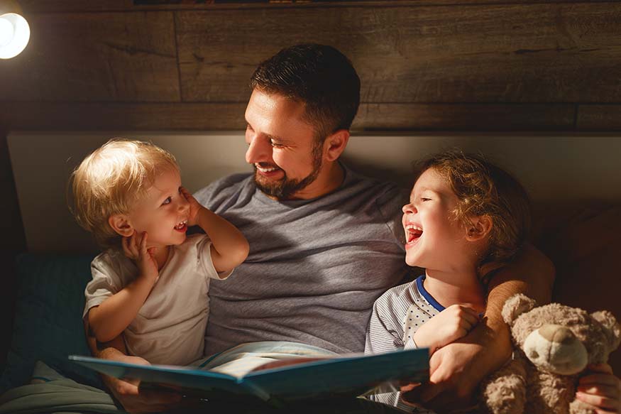A father reading a bedtime story to two young children.