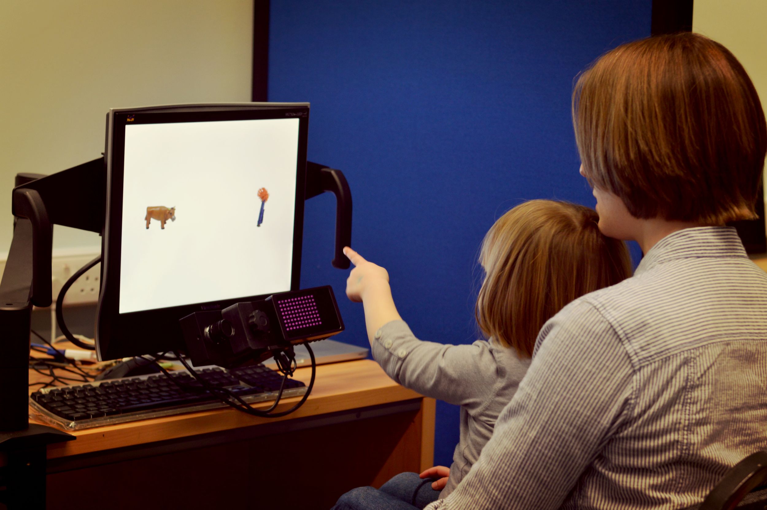 integrating-visual An adult holding a child pointing at a computer.