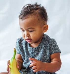 A toddler investigating a banana.
