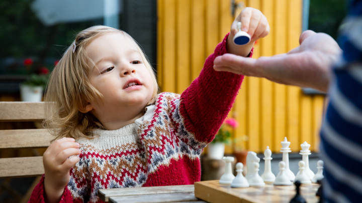 child_chess_720x405 A young child passing a chess piece to a parent.